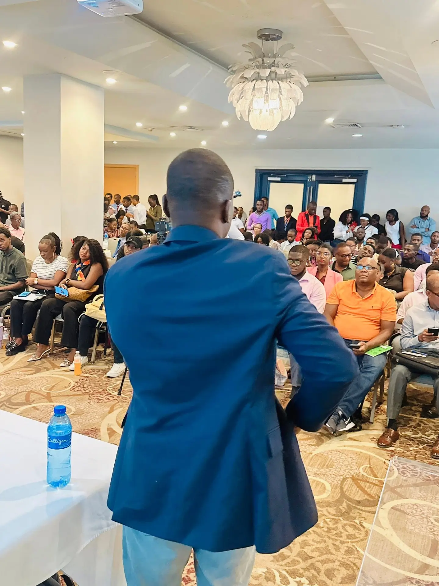 Intervenant de dos s'adressant a une salle de conference comble